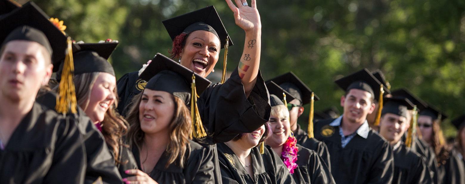 a graduate waves enthusiastically at crowd